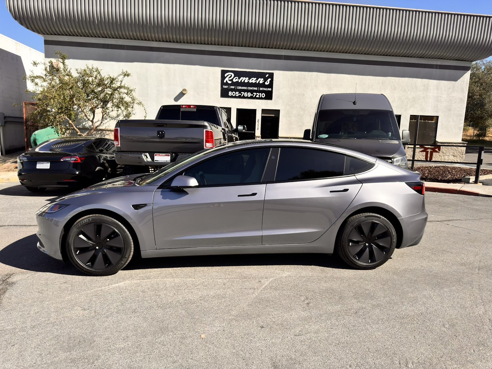 Gray Tesla Model 3 tinted outside Roman's shop